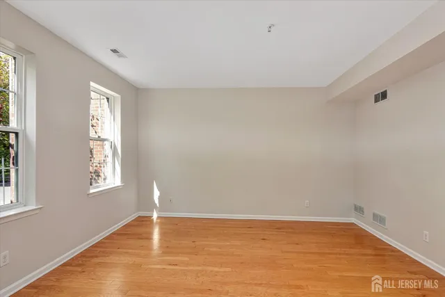 a view of an empty room with wooden floor and window
