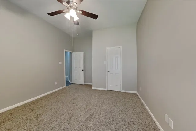 a view of an empty room and chandelier fan