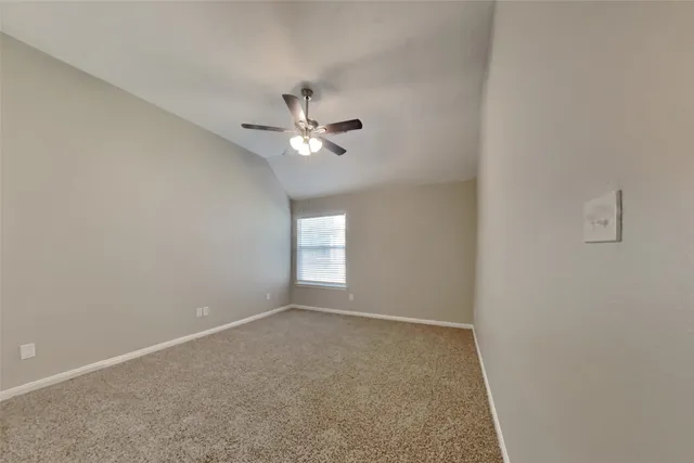 an empty room with a chandelier fan and windows