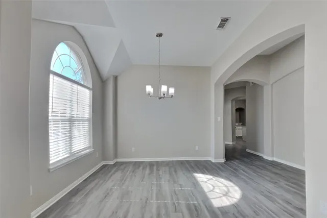 a view of a room with wooden floor chandelier and windows
