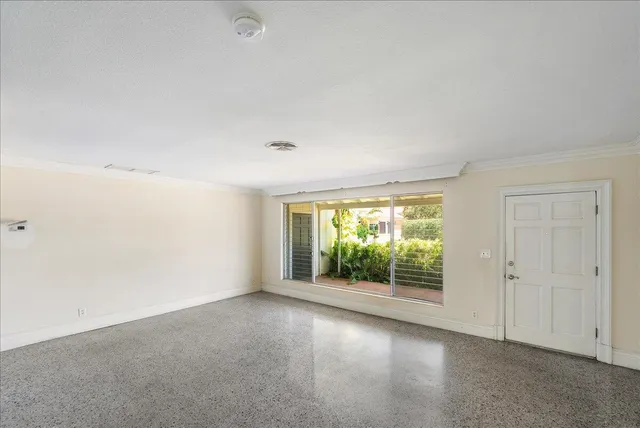 an empty room with a chandelier fan and windows
