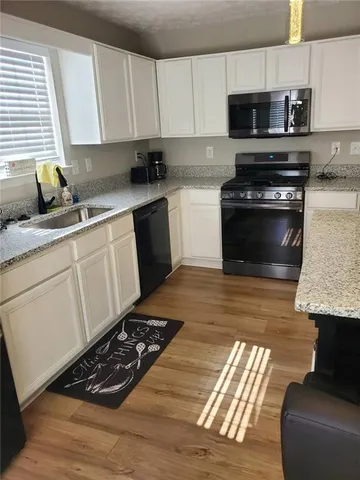 a kitchen with a stove a sink and a white cabinets