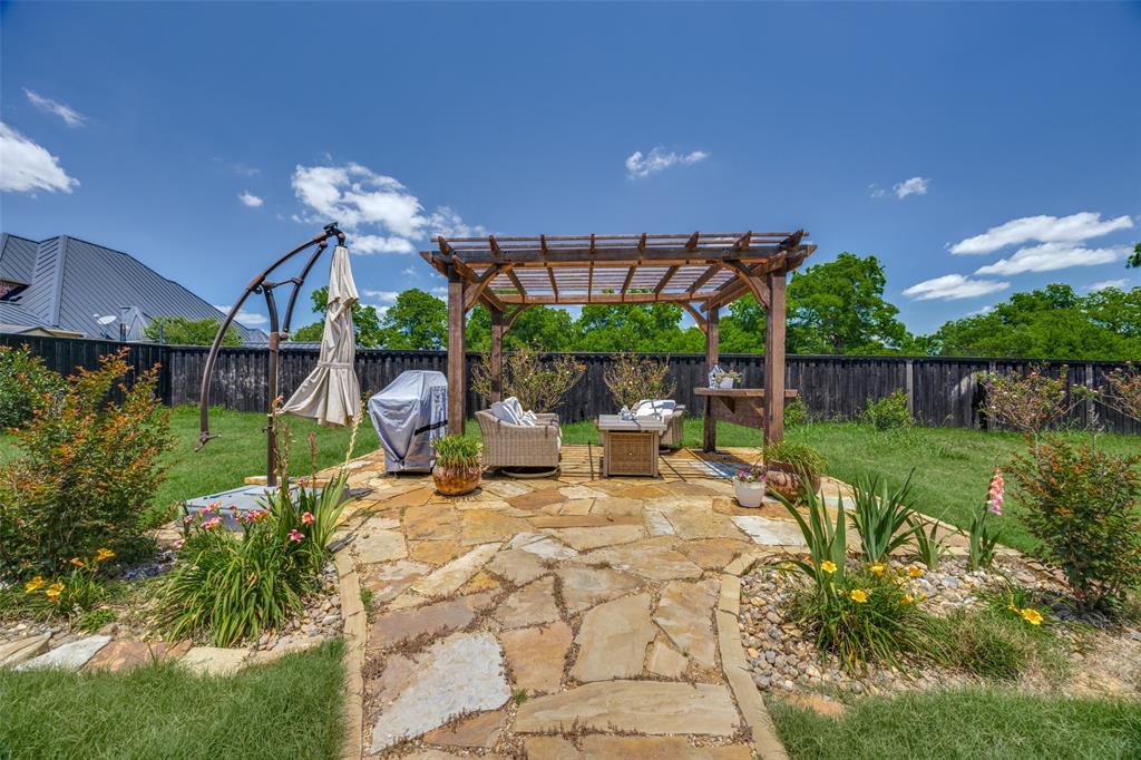 1105 Ranch Drive Bonham, TX 75418 - Photo 24 of 25 Expanded area of the patio, featuring a pergola and stone pathway with some lovely landscaping.