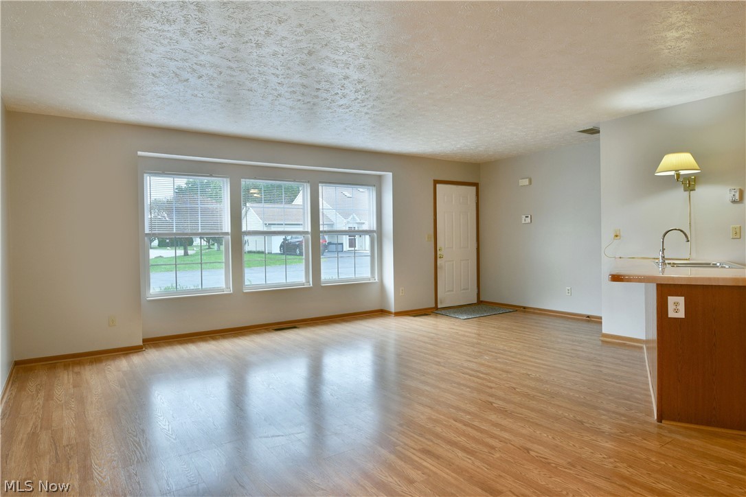 3287 Pheasant Run Road, Unit B Cortland, OH 44410 - Photo 25 of 45 Expansive room featuring wood-finish flooring, a series of three windows, and a built-in counter with sink and faucet
