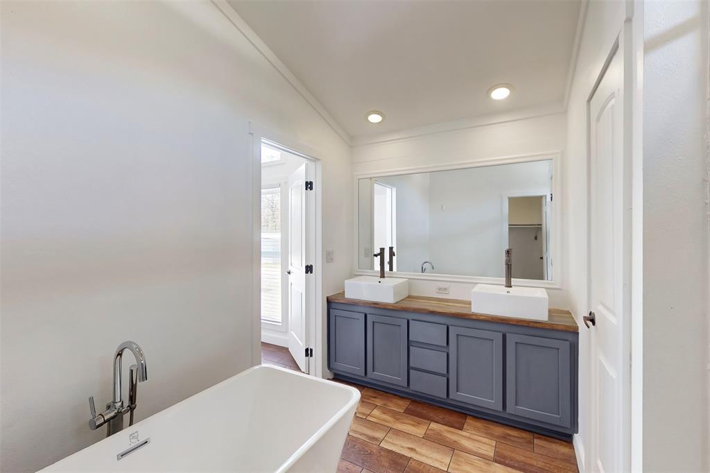 6715 Timberhaven Court Granbury, TX 76049 - Photo 22 of 40 a spacious bathroom with a granite countertop sink a mirror and a bathtub