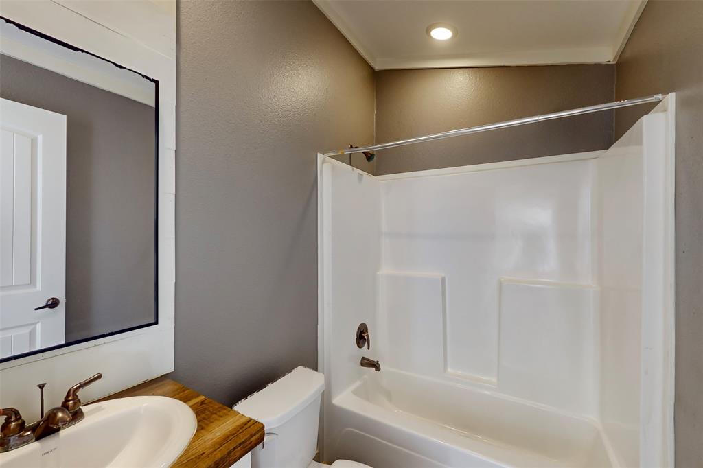 6715 Timberhaven Court Granbury, TX 76049 - Photo 32 of 40 a bathroom with a granite countertop sink mirror toilet and bathtub
