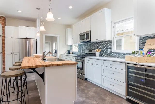 a kitchen with kitchen island granite countertop a sink a counter space and stainless steel appliances