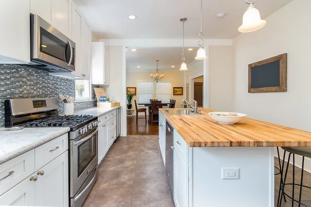 a kitchen with kitchen island granite countertop a stove top oven a sink a counter top space and cabinets