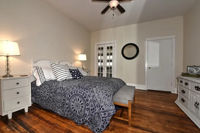 a bedroom with a bed and dresser with wooden floor