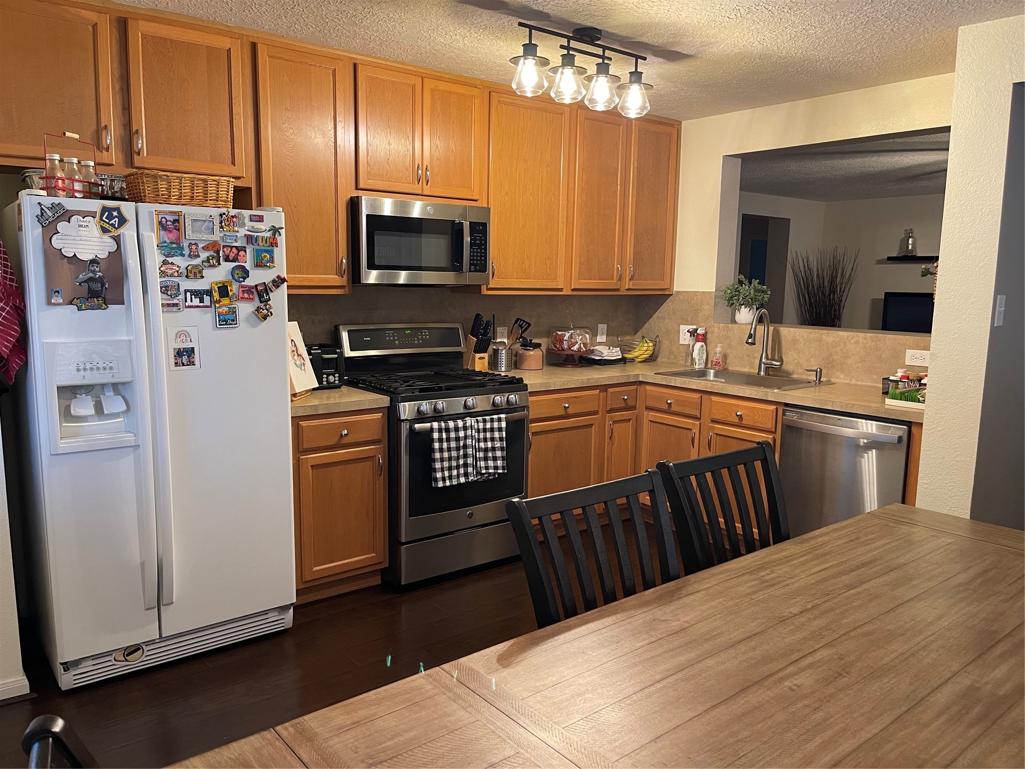 3310 Legends Wild Drive Spring, TX 77386 - Photo 11 of 40 a kitchen with stainless steel appliances a microwave a stove a sink dishwasher a refrigerator and cabinets with wooden floor