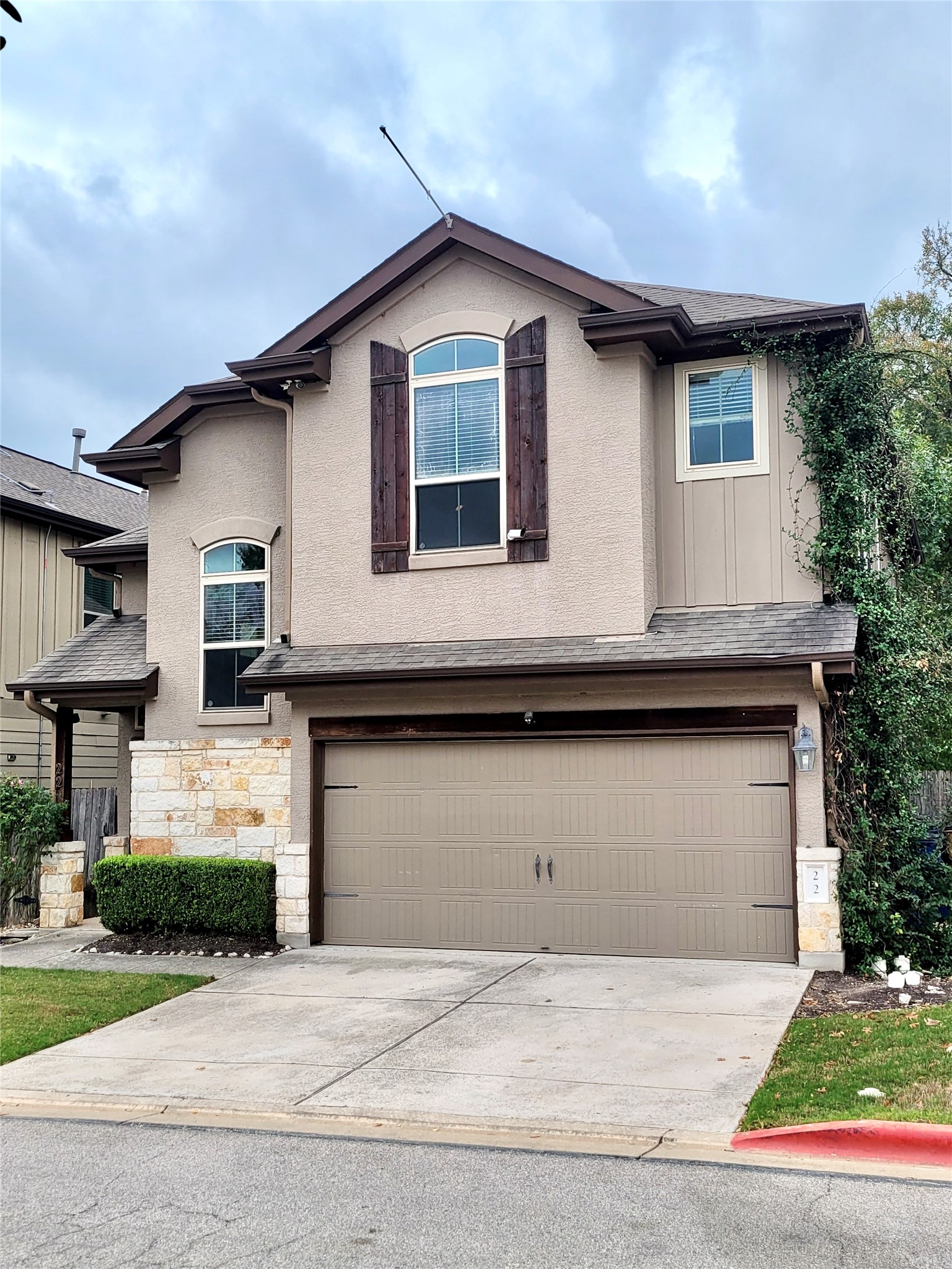 7337 Menchaca Road, Unit #22 Austin, TX 78745 - Photo 3 of 25 Traditional-style home with concrete driveway, stone siding, an attached garage, and roof with shingles