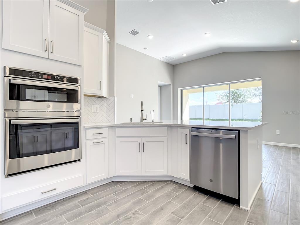 2675 Ridgetop Lane Clermont, FL 34711 - Photo 30 of 56 a kitchen with granite countertop white cabinets and white appliances