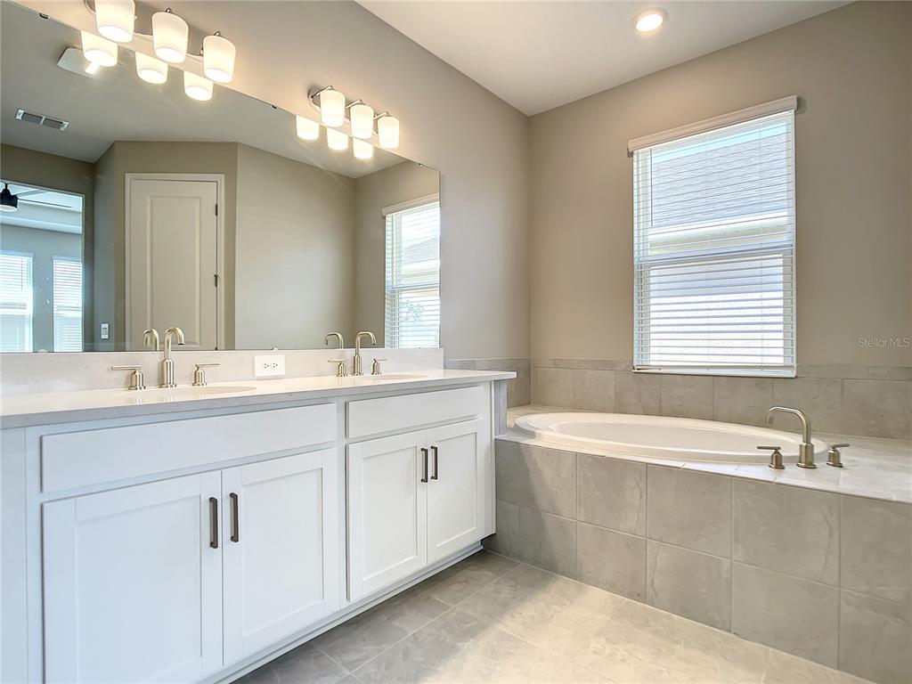 2675 Ridgetop Lane Clermont, FL 34711 - Photo 48 of 56 a spacious bathroom with a double vanity sink a mirror and a bathtub
