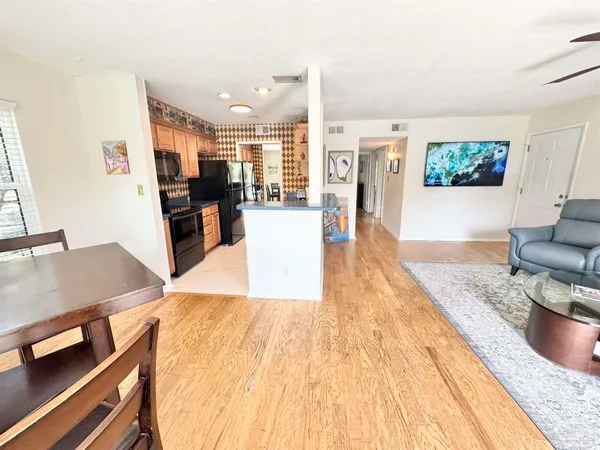 a living room with stainless steel appliances kitchen island granite countertop furniture and a wooden floor
