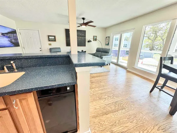 a living room with stainless steel appliances granite countertop sink microwave and view of living room