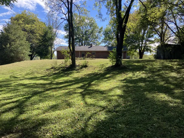 a backyard of a house with a yard and large trees