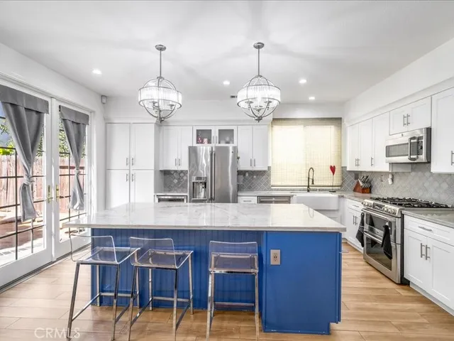 a large kitchen with stainless steel appliances granite countertop a stove oven a sink dishwasher and a dining table with wooden floor