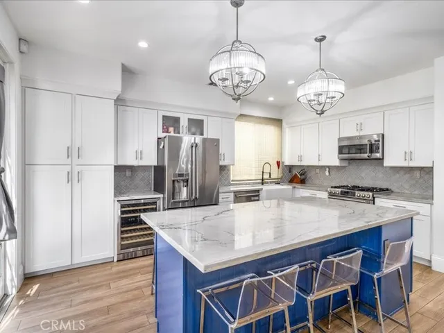 a kitchen with stainless steel appliances granite countertop a kitchen island a stove a refrigerator a sink dishwasher a dining table and chairs with wooden floor