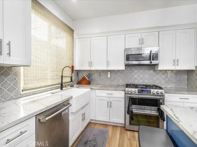 a kitchen with white cabinets and appliances