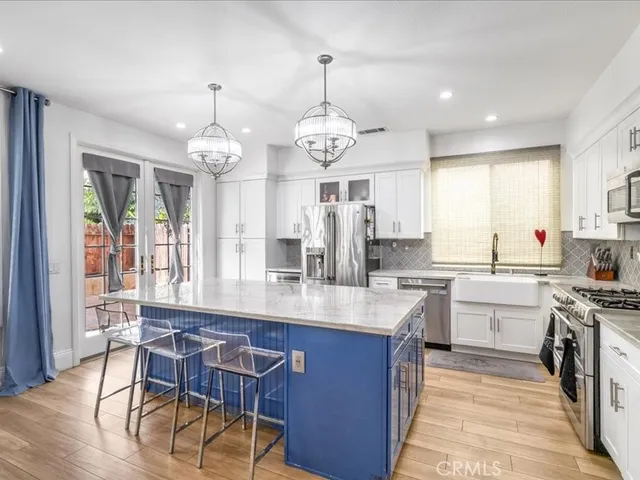 a kitchen with stainless steel appliances granite countertop a stove a sink dishwasher a dining table and chairs with wooden floor