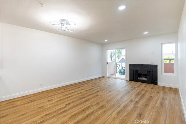 a view of an empty room with wooden floor fireplace and a window