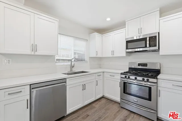 a kitchen with stainless steel appliances granite countertop grey cabinets a sink a stove a microwave and cabinetry