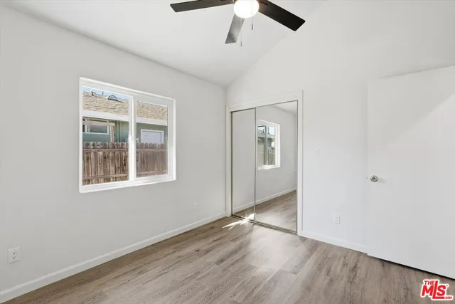 an empty room with wooden floor cabinet and windows