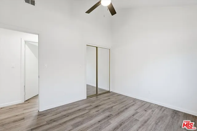 an empty room with wooden floor ceiling fan and window