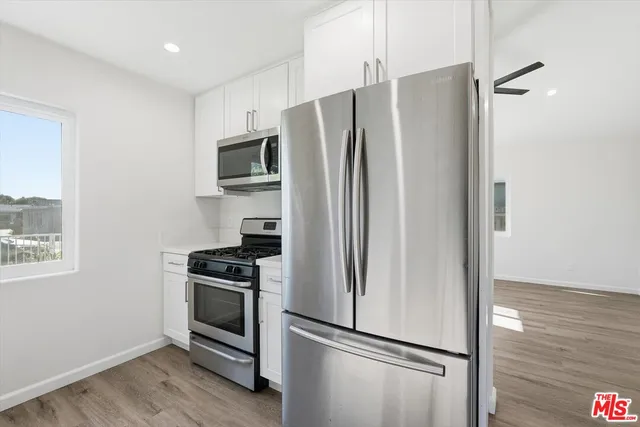 a view of kitchen with refrigerator stove and wooden floor