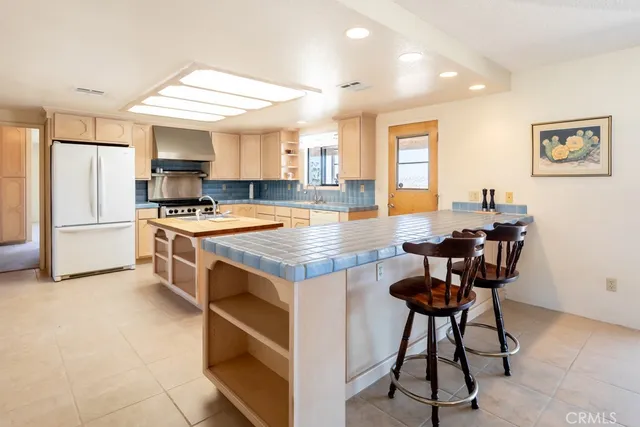a open kitchen with kitchen island a stove a sink dishwasher and white cabinets with wooden floor