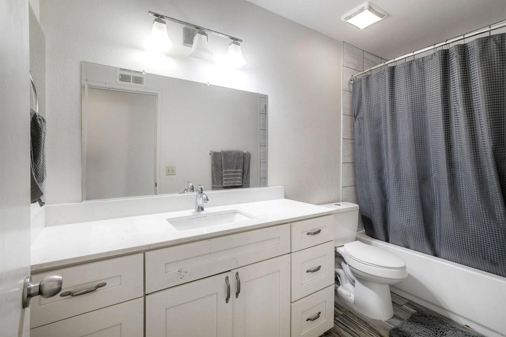 4413 Point Degada Oceanside, CA 92058 - Photo 15 of 31 a bathroom with a sink a toilet a mirror and shower curtain