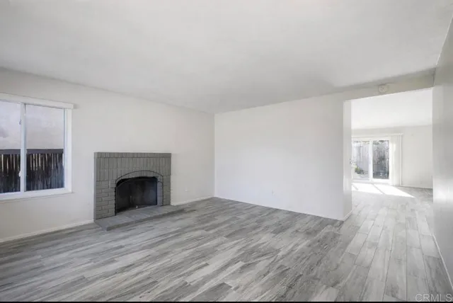 a view of empty room with wooden floor and fireplace