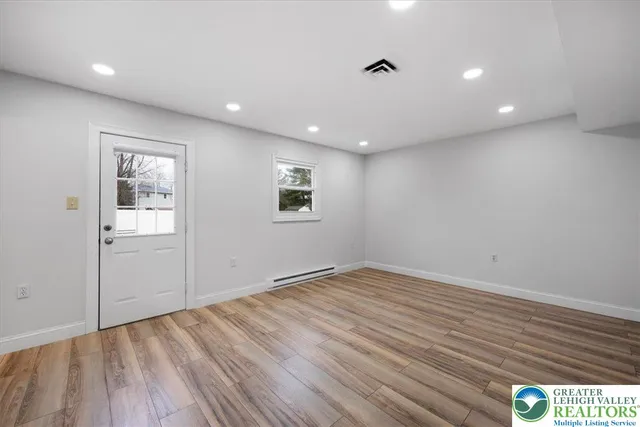 a view of an empty room with wooden floor and a window