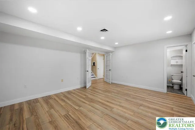 a view of an empty room with wooden floor and closet