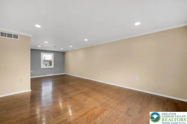 a view of an empty room with wooden floor and kitchen