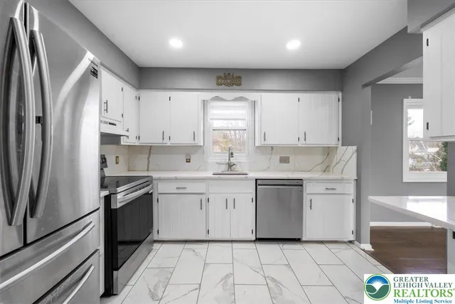 a kitchen with white cabinets appliances and a sink