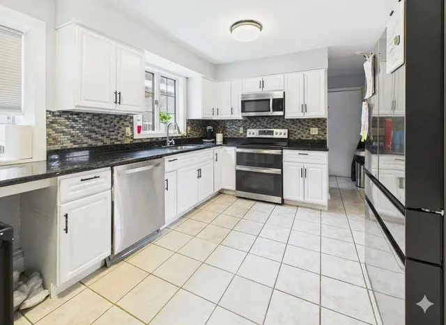 a kitchen with stainless steel appliances granite countertop a stove a sink and white cabinets