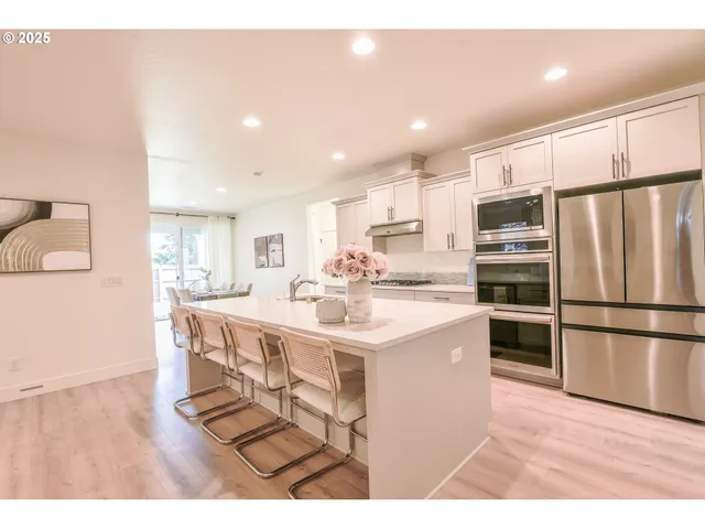 a kitchen with stainless steel appliances a refrigerator a stove a sink dishwasher with a dining table and chairs