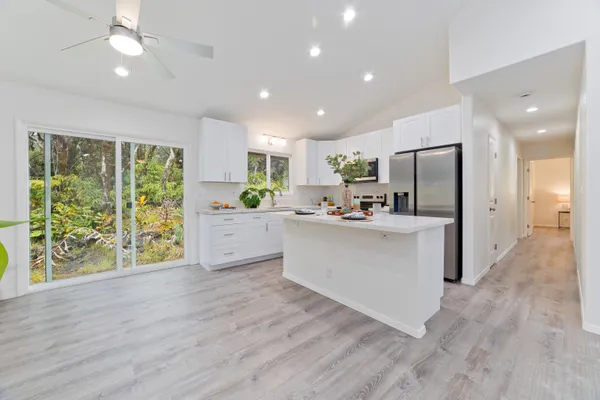 a kitchen with stainless steel appliances a refrigerator a sink dishwasher a stove and white cabinets with wooden floor