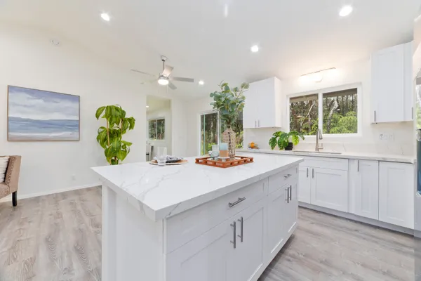 a kitchen with kitchen island granite countertop a sink a counter top space and living room view