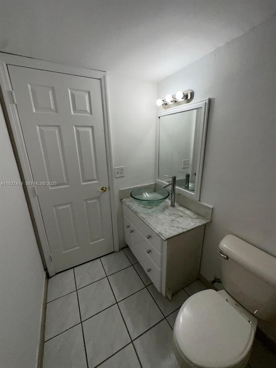 5665 West 20th Avenue, Unit 308 Hialeah, FL 33012 - Photo 15 of 17 a bathroom with a granite countertop sink toilet and shower