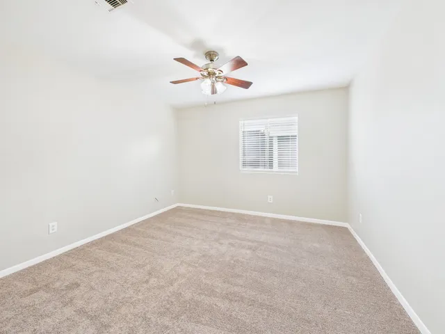 an empty room with closet and a ceiling fan