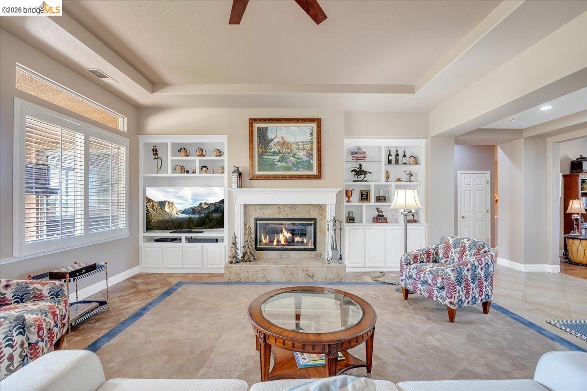 158 Rock Ridge Lane Copperopolis, CA 95228 - Photo 15 of 72 Living space featuring a central fireplace with stone surround and mantle, flanked by built-in shelving and cabinetry