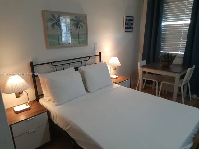 a bedroom with a bed and a lamp on dresser