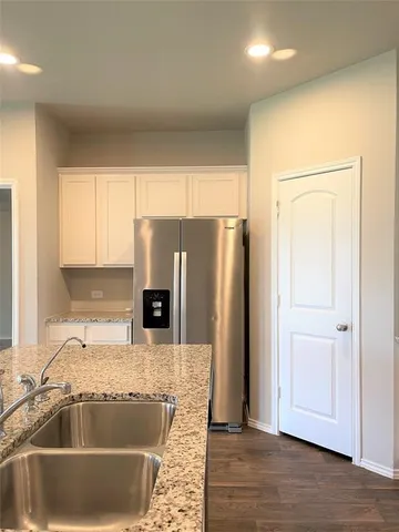 a kitchen with granite countertop a refrigerator and a sink