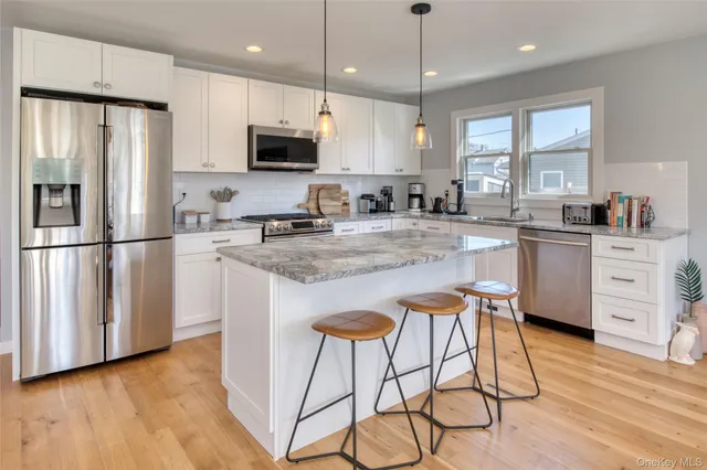 a kitchen with stainless steel appliances granite countertop a refrigerator a stove a sink dishwasher and a microwave with wooden floor