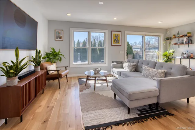 a living room with furniture large windows and wooden floor