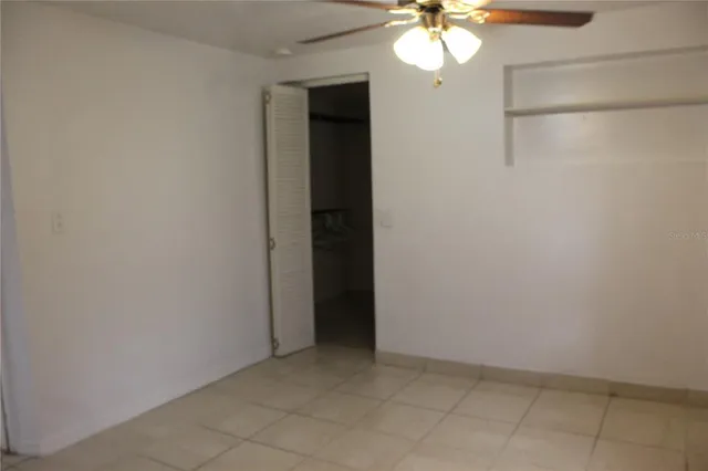 a view of an empty room with a chandelier fan