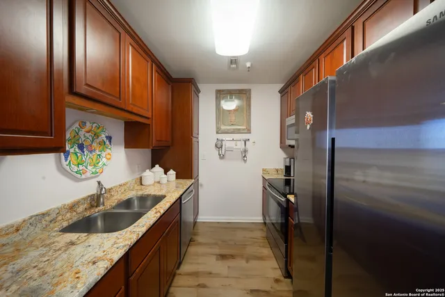 a kitchen with stainless steel appliances granite countertop a sink and a refrigerator