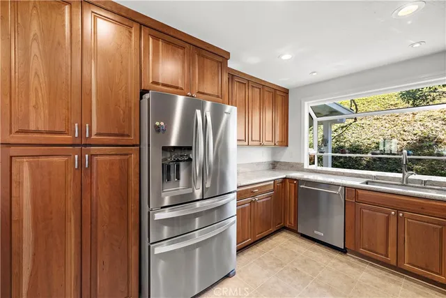 a kitchen with granite countertop wooden cabinets stainless steel appliances and a window